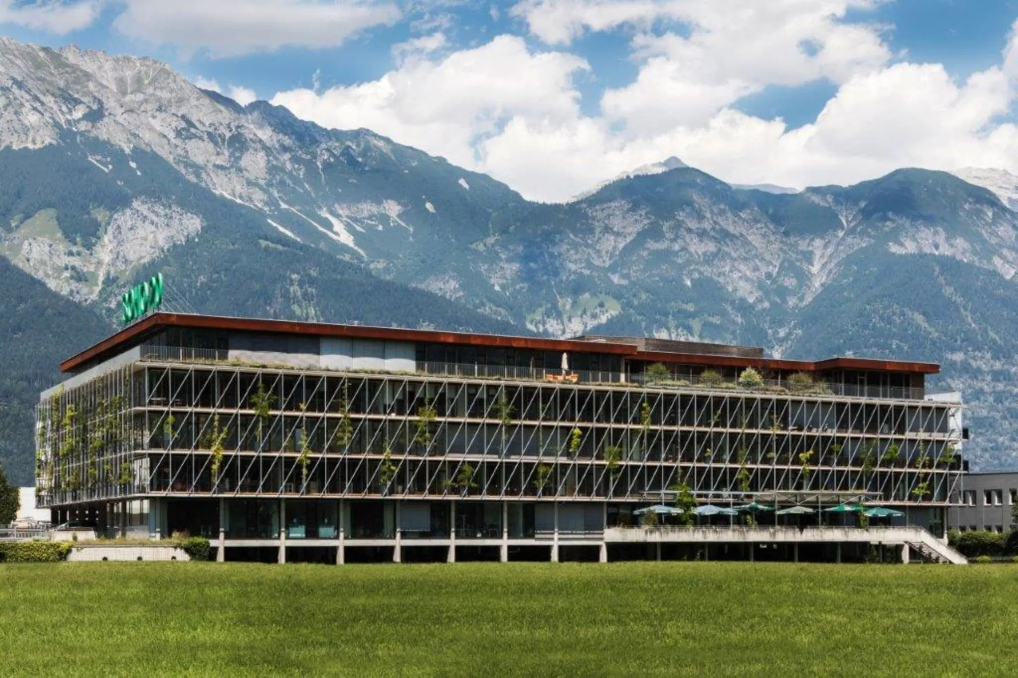 Das Bürogebäude SOHO 2.0 in Innsbruck mit begrünter Fassade, dahinter die Nordkette